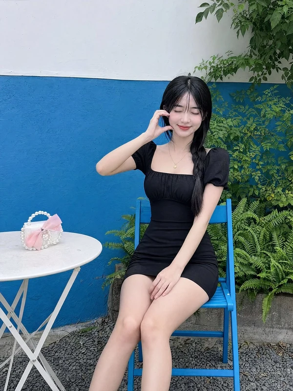 Woman in a black dress seated in a blue folding chair